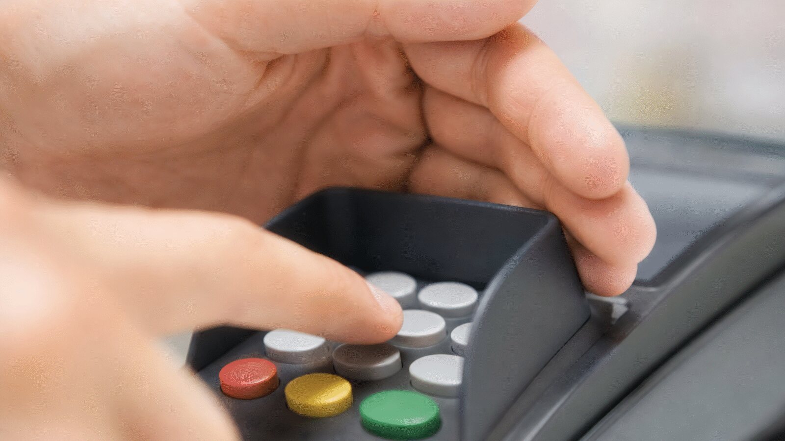 Ruka zakrývá klávesnici platebního terminálu při zadávání PIN kódu